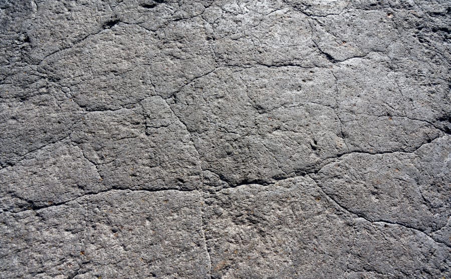 A weathered grey surface broken by a network of cracks